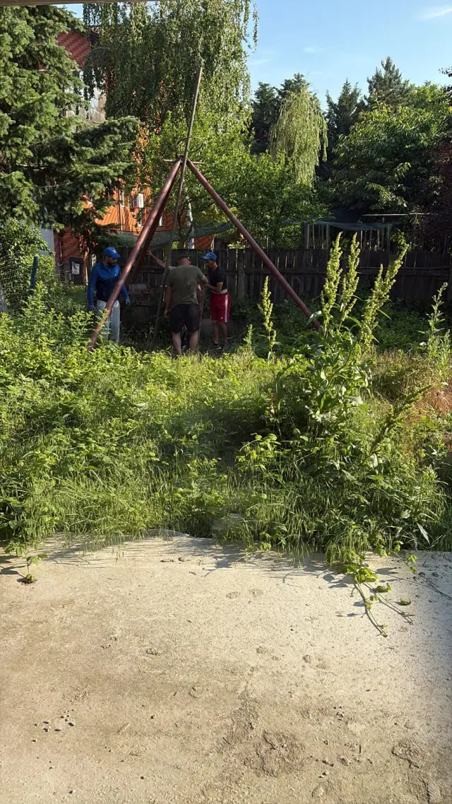 Echipa de foraj lucrând cu trepiedul într-o grădină